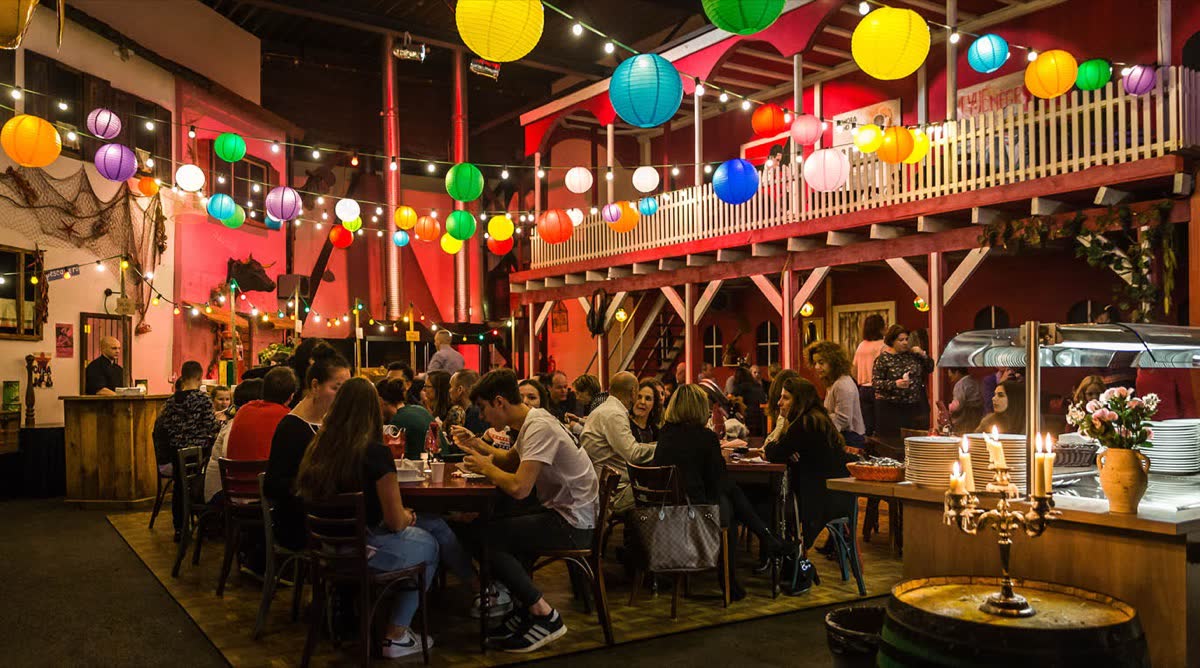 Gasten aan tafel in een feestelijk verlichte zaal met lampionnen